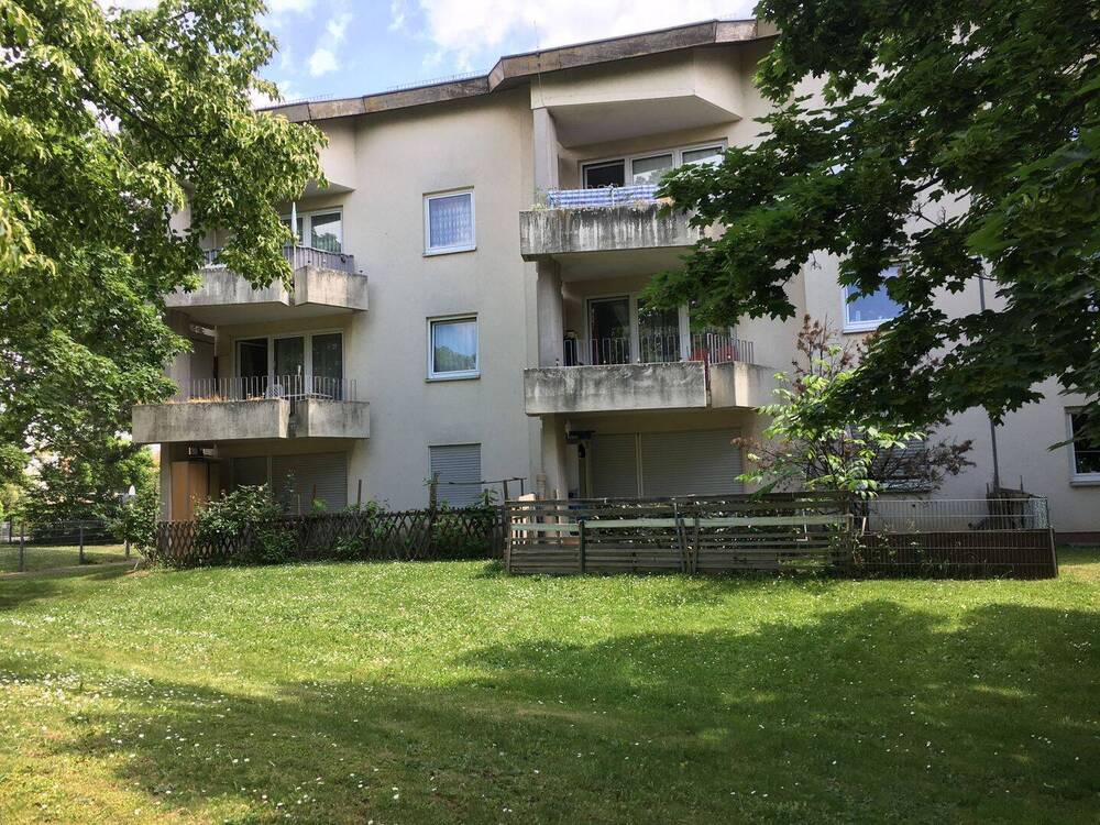 Gebäude Rückseite des mehrstöckigen Wohnhauses mit Blick in die Grünanlage mit Sträuchern
